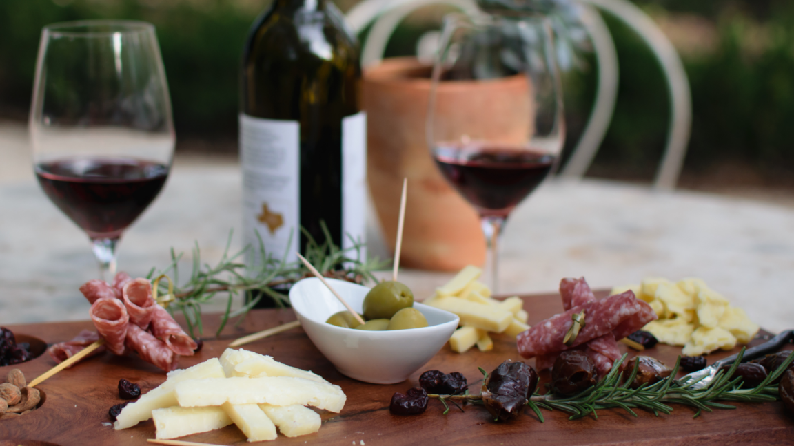 Image of two wine glasses and cheesboard with texas wine bottle at texas winery